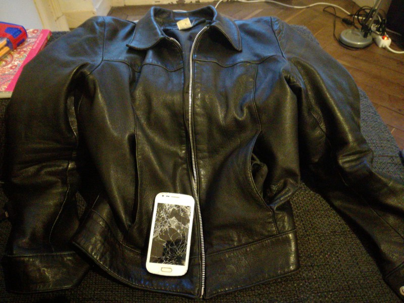Veste en cuir noire avec un portable Samsung blanc cassé et étend trouvé a place cathédrale