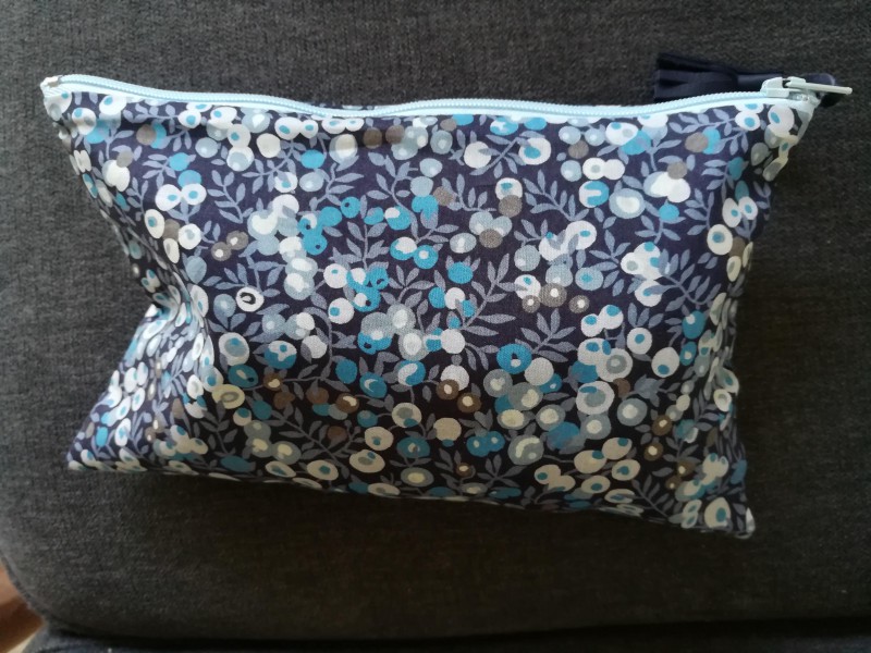Petite pochette zippé bleu chamarré contenant un drap noir d'allaitement
