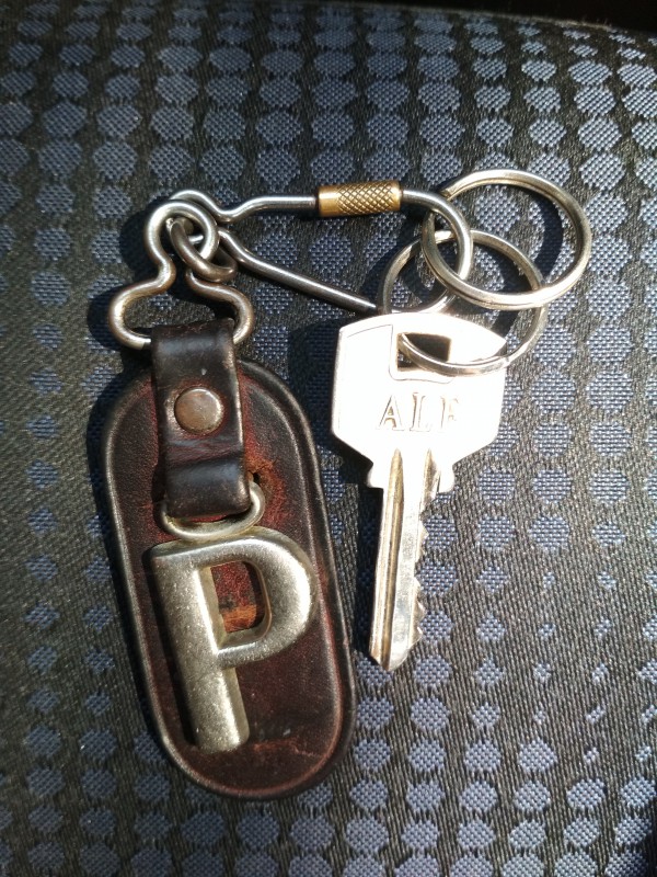 Clé avec porte-clé marron avec un grand P. Je pense qu'il s'agit d'une clé de porte d'entrée.
