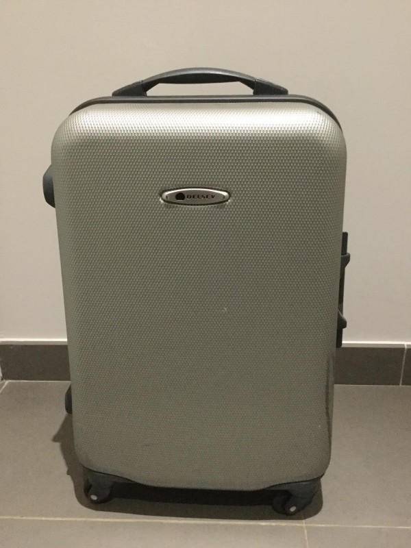 Grosse valise coque en dur gris clair revêtement nid d’abeille marque Delsey aéroport Orly