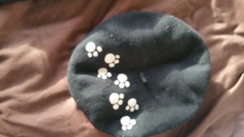 perdu béret noir avec motif pattes de chat blanches sur le dessus