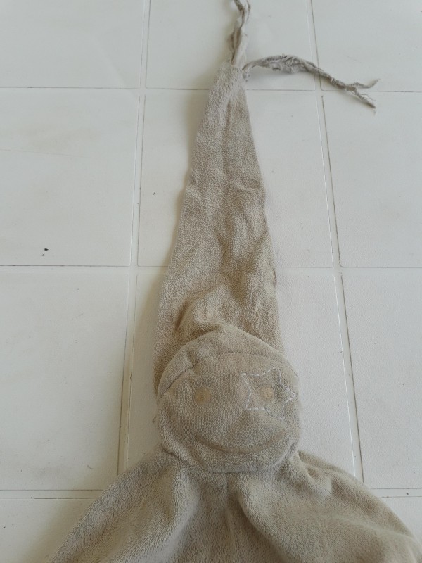 Doudou lutin beige avec une étoile autour de l'oeil mordillé sur le chapeau