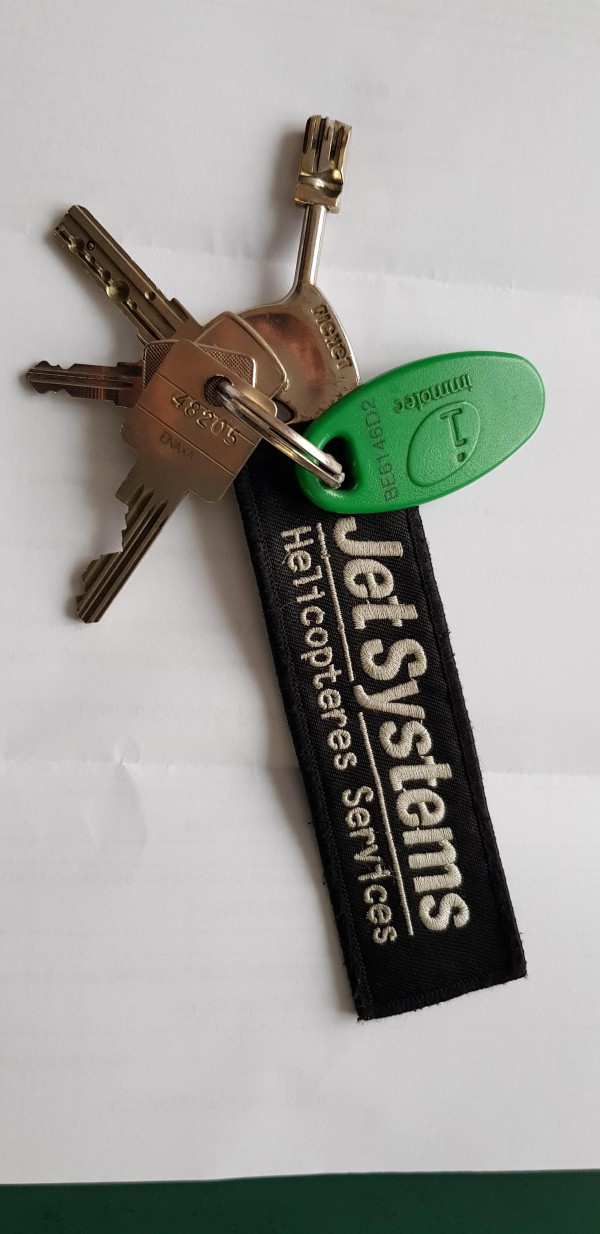 Un trousseau de 4 clés avec un badge électronique rouge et une étiquette tissu rouge marqué JetSystems Helicopteres Services