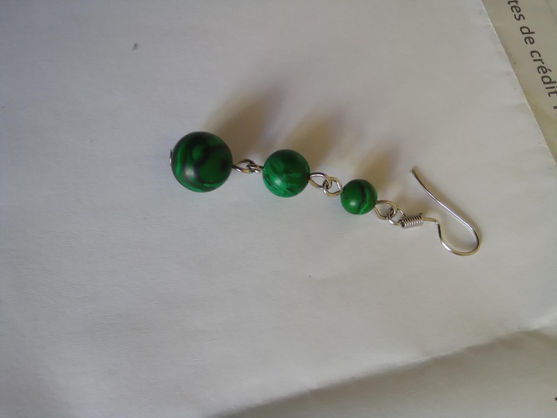 une boucle d’oreille en malachite verte composée de trois perles sphériques de dimensions croissantes