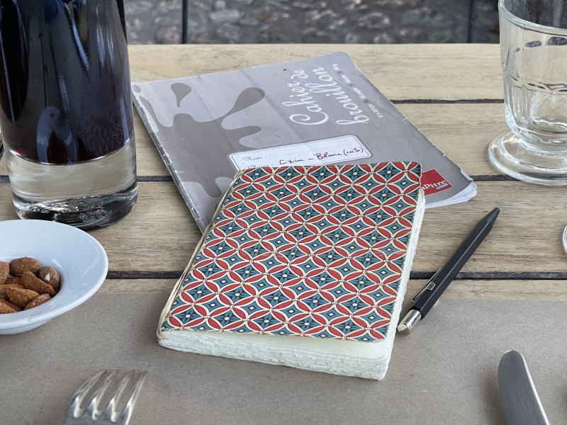 Un carnet d'écriture 10X15 avec des motifs géométriques rouge et bleu en losange en couverture..